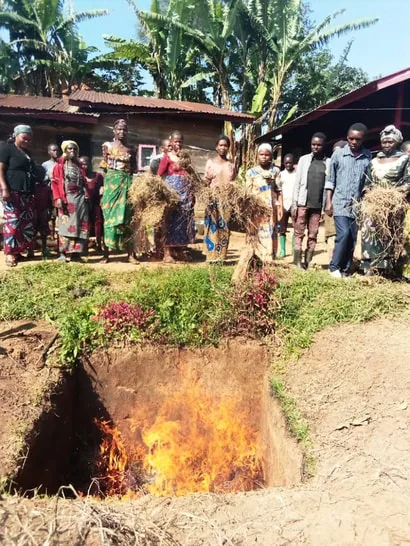 Group of farmers learning how to make biochar in a trench