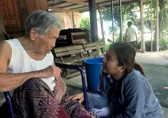 A moment of companionship between Access to Care home visit with disabled woman in wheelchair who lives alone and in poverty.